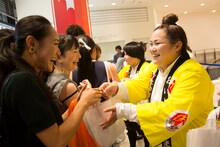 会見終了後に街頭で福井名産品を配布するおかずクラブ。(c)吉本興業