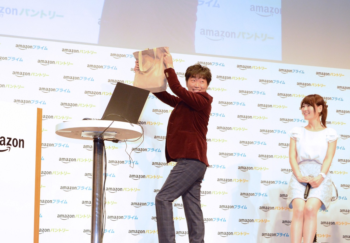 軽くなった買い物袋を掲げるスピードワゴン小沢。