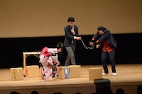 低周波治療器を付けてダンボール積み上げに挑戦する前田希美（左）とアイパー滝沢（右）。