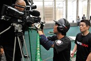 撮影中のテレビカメラのレンズにサインを書くスピードワゴン小沢。