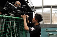 撮影中のテレビカメラのレンズにサインを書くスピードワゴン井戸田。