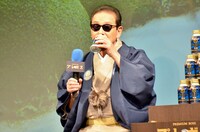 「プレミアムボス」を試飲するタモリ。