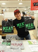 自身がプロデュースした「MEAT SOLDIER（ミートソルジャー）Tシャツ」を掲げる寺門ジモン。
