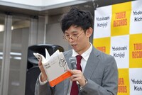 完成した本著を初めて見るという芦沢。