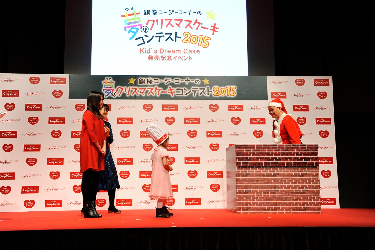 銀座コージーコーナーのイベントで、サンタクロースに扮して煙突の中から出現する千原せいじ（右端）。