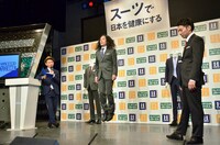 「ストレス対策スーツ」の動きやすさを実証するため、ジャンプを繰り返すギャグで会場の笑いを誘うピース又吉（中央）。