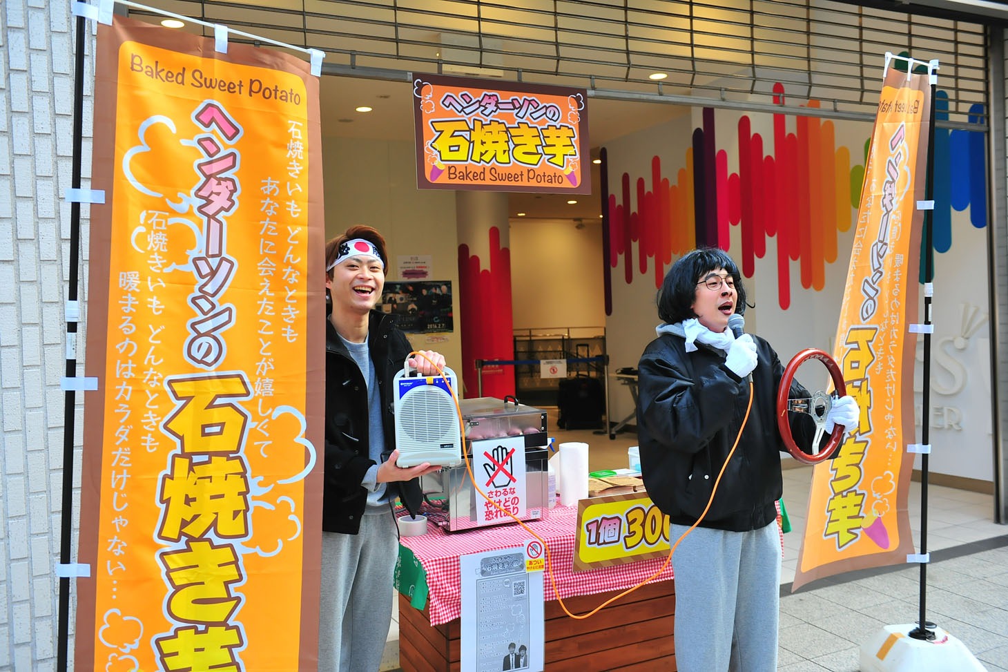 「石焼き芋の歌」を歌いながら焼き芋販売を行うヘンダーソン。