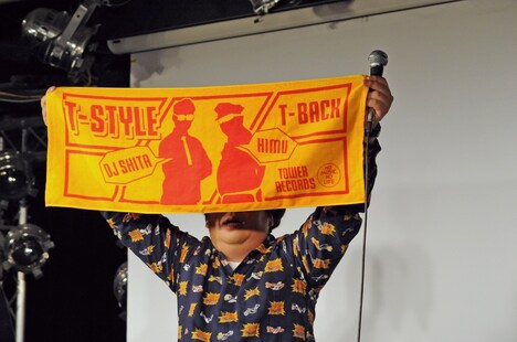T-STYLEのオリジナルタオルを客席に見せるバナナマン日村。