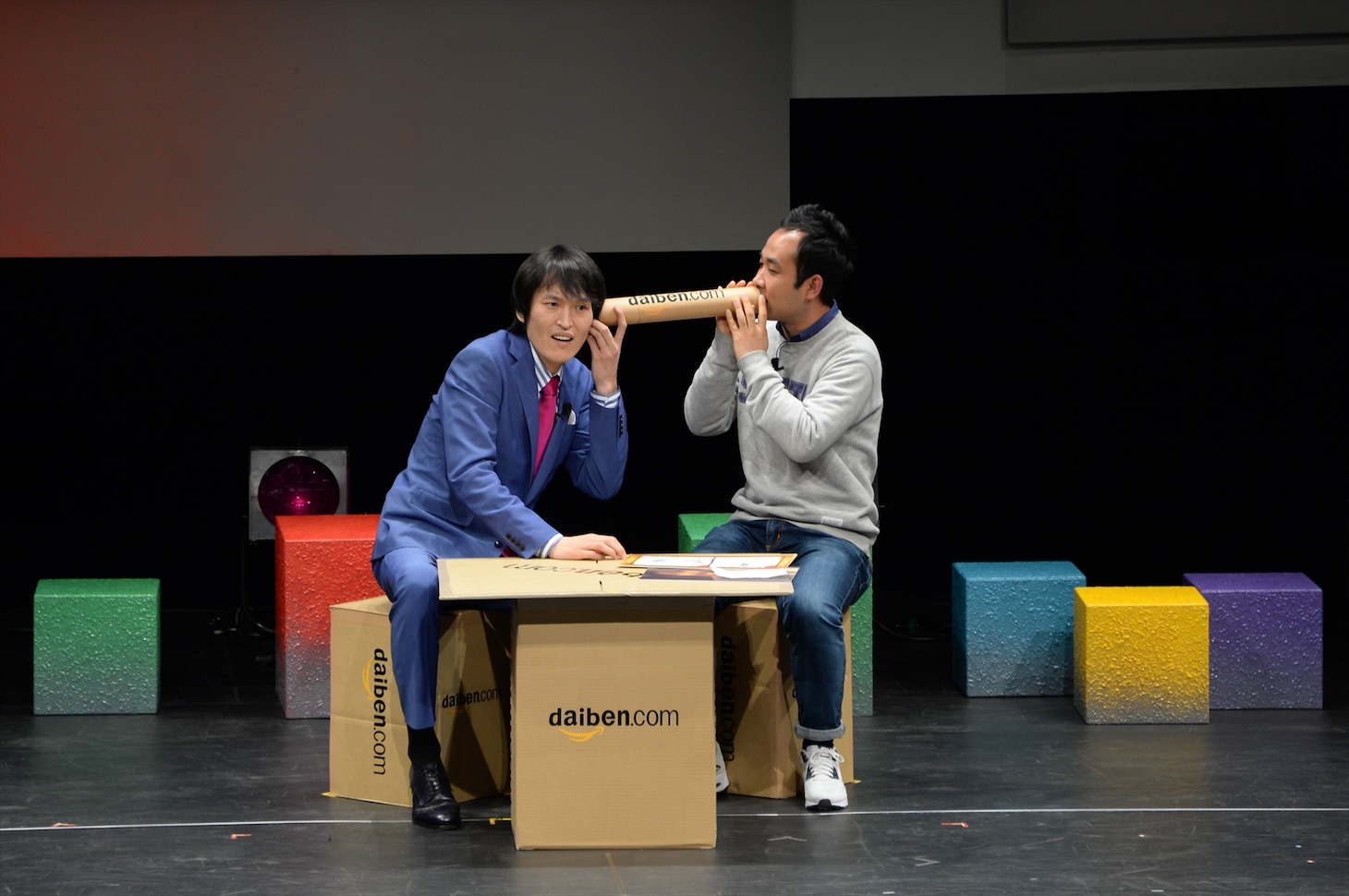 フジテレビの竹内誠氏が手掛けたステージ「daiben.com」で、気象予報士の天達武史氏（右）の耳打ちを受ける千原ジュニア（左）。