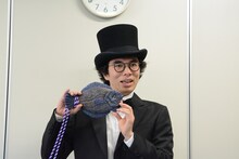 自身の作品「カレイPhone」を持った片桐仁。