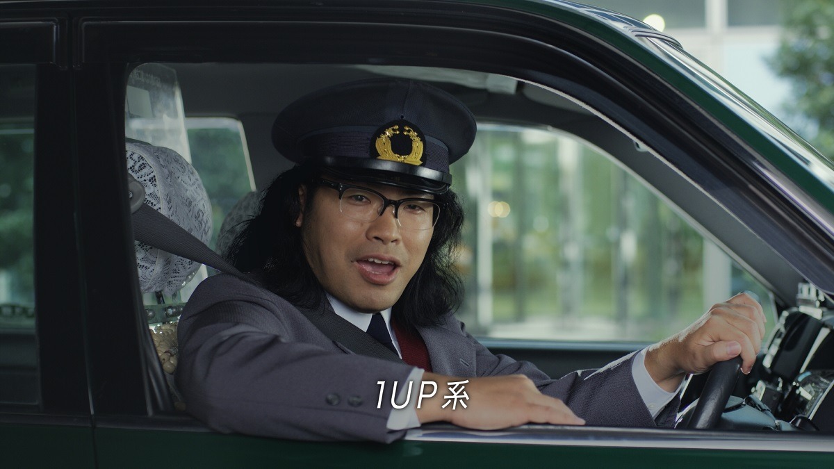 「1UP」の新CM「海外出張で1UP」篇のワンシーン。