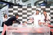 Galaxy S7 edgeを渡そうとする堤浩幸氏と、手を伸ばすダチョウ倶楽部・上島。