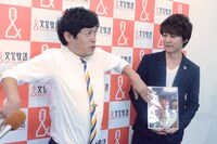 囲み取材中、記者からのリクエストで「肘神様」を披露する流れ星ちゅうえい（左）。