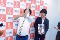 囲み取材中、記者からのリクエストで「肘神様」を披露する流れ星ちゅうえい（左）。