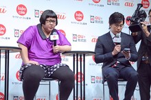 「kabu.com for au」を体験するメイプル超合金カズレーザー（右）。