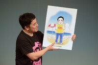 東村アキコからプレゼントされたイラストを紹介する与座よしあき。
