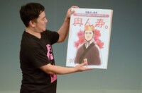 東村アキコからプレゼントされたイラストを紹介する与座よしあき。