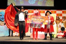 仮装コンテストの優勝者（中央）と、ますだおかだ。