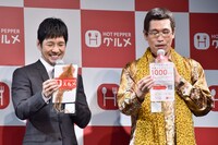 街頭で配布される「ホットペッパースルメ」を手にする（左から）西島秀俊、ピコ太郎。