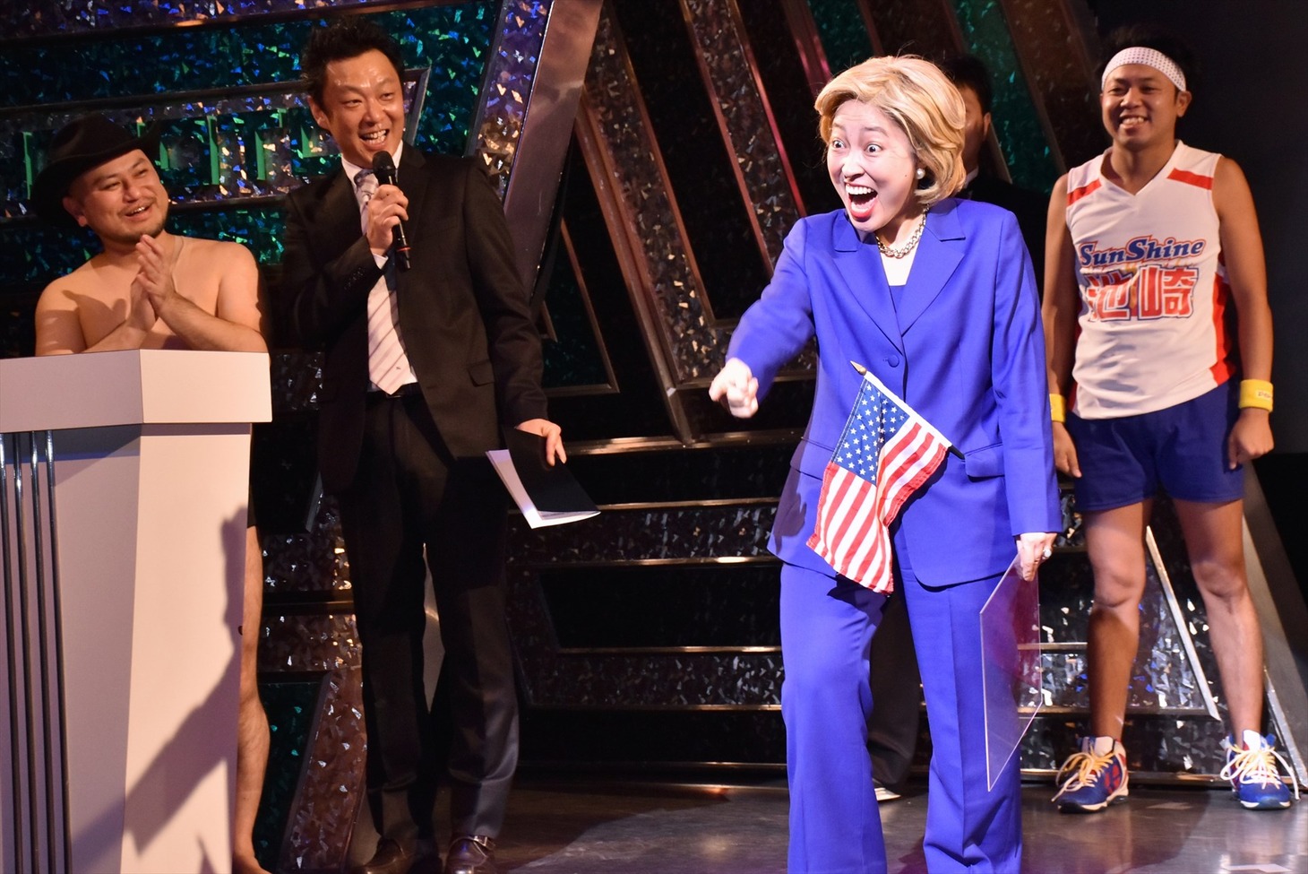 ヒラリー・クリントンに扮し「R-1というアメリカンドリームを手にしたい」と話す石井てる美（右から2人目）。
