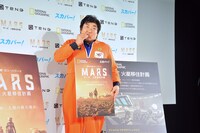 サンドウィッチを食べながら写真撮影に応じる草野伸也。