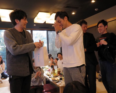 とろサーモンの「M-1」優勝を祈願したお守りを村田に手渡す林遣都（左）。