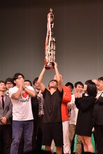 優勝トロフィーを高らかに掲げるアルコ＆ピース酒井（中央）。