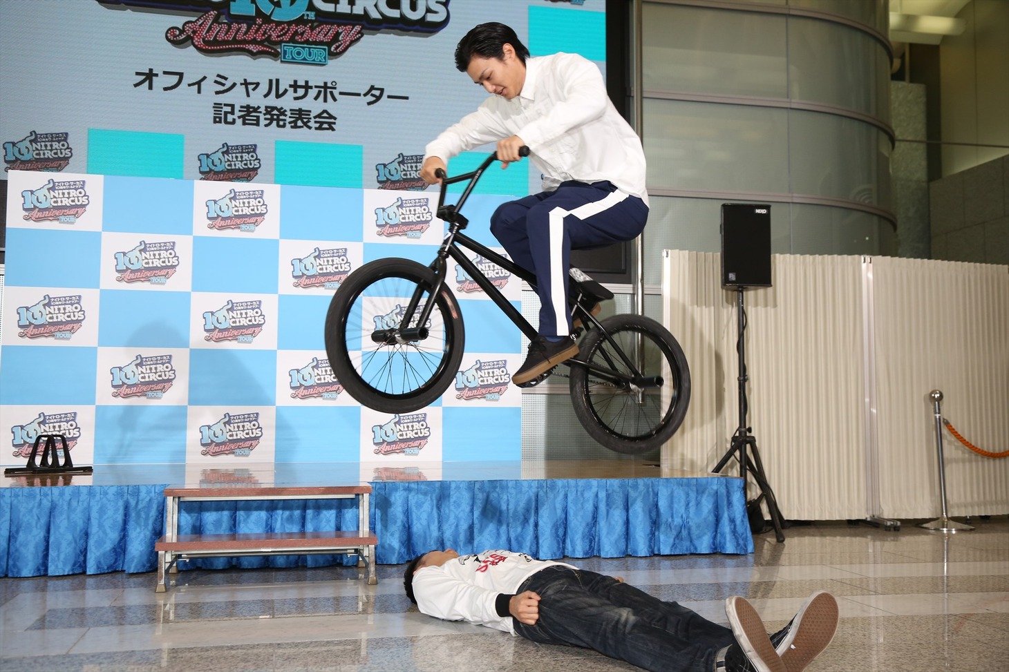 「ナイトロ・サーカス 10周年ワールドツアー 東京/大阪公演オフィシャルサポーター就任 記者発表会」で野村周平（上）にBMXで飛び越えられるピース綾部（下）。