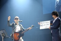 上々軍団。「ランドマークタワーで秘密のデート」を歌唱するさわやか五郎（左）と歌詞カードをめくる鈴木（右）。（写真提供：アップフロント）