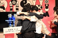 抱擁する「チーム 世界湯」のメンバー。