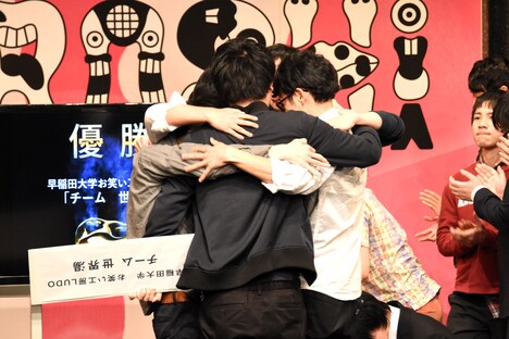 抱擁する「チーム 世界湯」のメンバー。