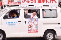 選挙カーの中から手を振るANZEN漫才みやぞん。