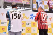 「北海道命名150年」仕様の北海道日本ハムファイターズと北海道コンサドーレ札幌のユニフォームを着るタカアンドトシ。