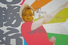 巨大絵馬型のパネルに顔をハメるメイプル超合金カズレーザー。