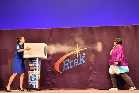 SHELLY（左）から空気砲を食らいながら、空気砲へにじり寄るメイプル超合金・安藤なつ（右）。