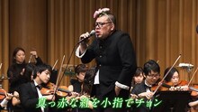 オーケストラの演奏で歌う野性爆弾くっきー。