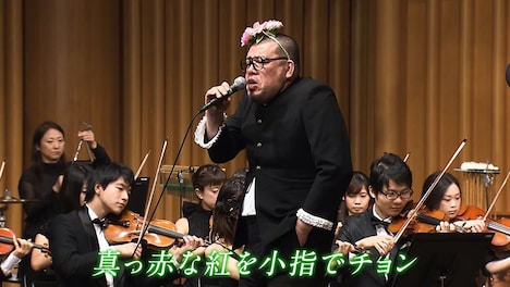 オーケストラの演奏で歌う野性爆弾くっきー。