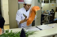 舞台裏でキングサーモンをさばく犬の心・いけや。