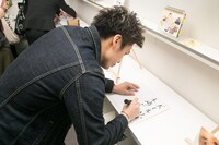 色紙にことわざを書く木崎。