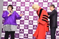 特製の赤いローブを同志社大学副学長の藤澤義彦氏（右）に着せてもらうカズレーザー（中央）。