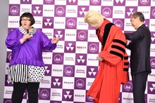 特製の赤いローブを同志社大学副学長の藤澤義彦氏（右）に着せてもらうカズレーザー（中央）。