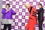 特製の赤いローブを同志社大学副学長の藤澤義彦氏(右)に着せてもらうカズレーザー(中央)。