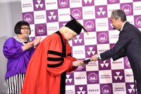 同志社大学副学長の藤澤義彦氏（右）に1日学長の委嘱状を手渡されるカズレーザー（中央）。