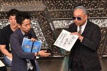 「海の家あるある」を書いた色紙を、お題を提供したファンにプレゼントするレイザーラモンRG（右）。