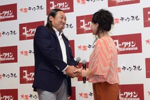 会見にて握手を交わすロバート秋山（左）と友近（右）。