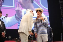 ベンジャミン・ボーナス（左）の小指を唇に当てられるカジヒデキ。