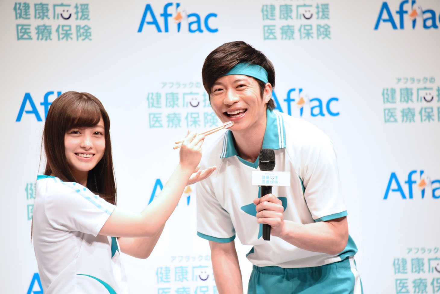 「あーん」の瞬間がフォトタイムになり、戸惑いながらも笑顔を見せる橋本環奈（左）と田中圭（右）。