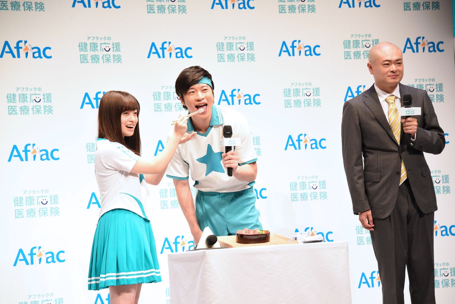 橋本環奈と田中圭のフォトタイム中、どんな顔をすればいいかわからなくなるあばれる君（右）。