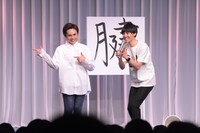 「腱」という字の前でポーズを決める祇園。