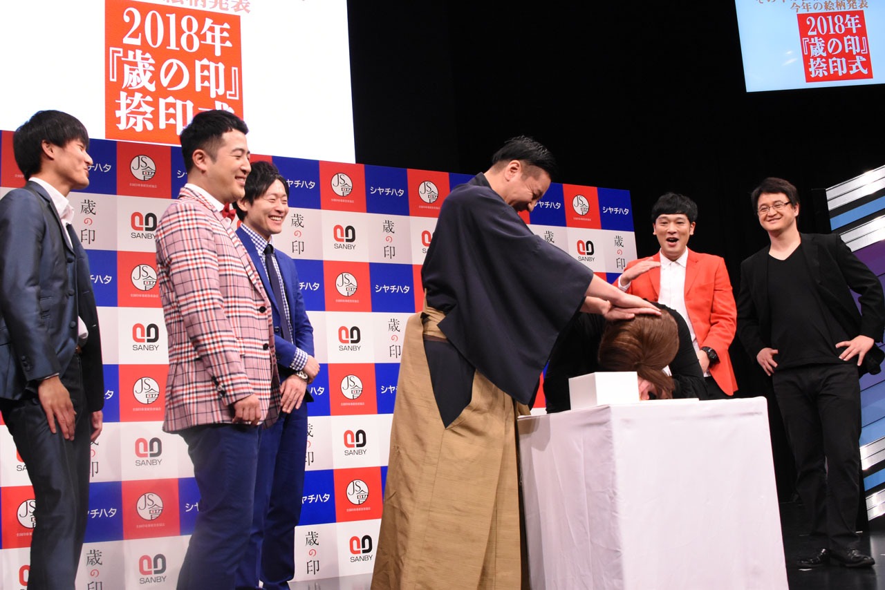ハンコを押す松尾の頭に手を添えるチョコプラ長田。